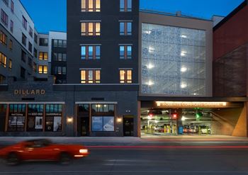 A red car is driving past a building